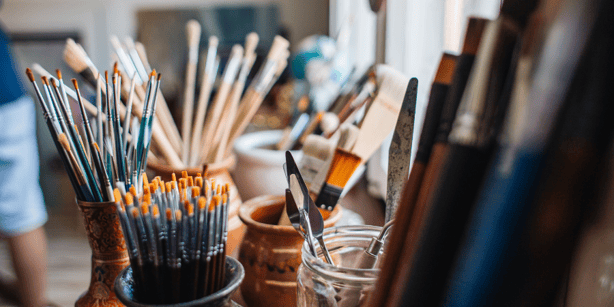 Paint brushes in jars in an art studio.