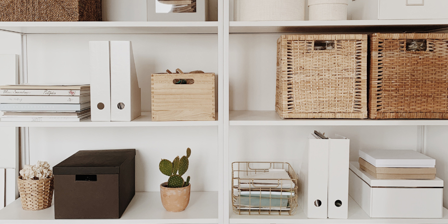 An organized white shelving unit with boxes and bins.