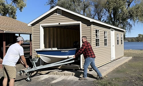 Two men pulling a boat from a Dakota Storage garage, showing spacious design and durable outdoor storage solution